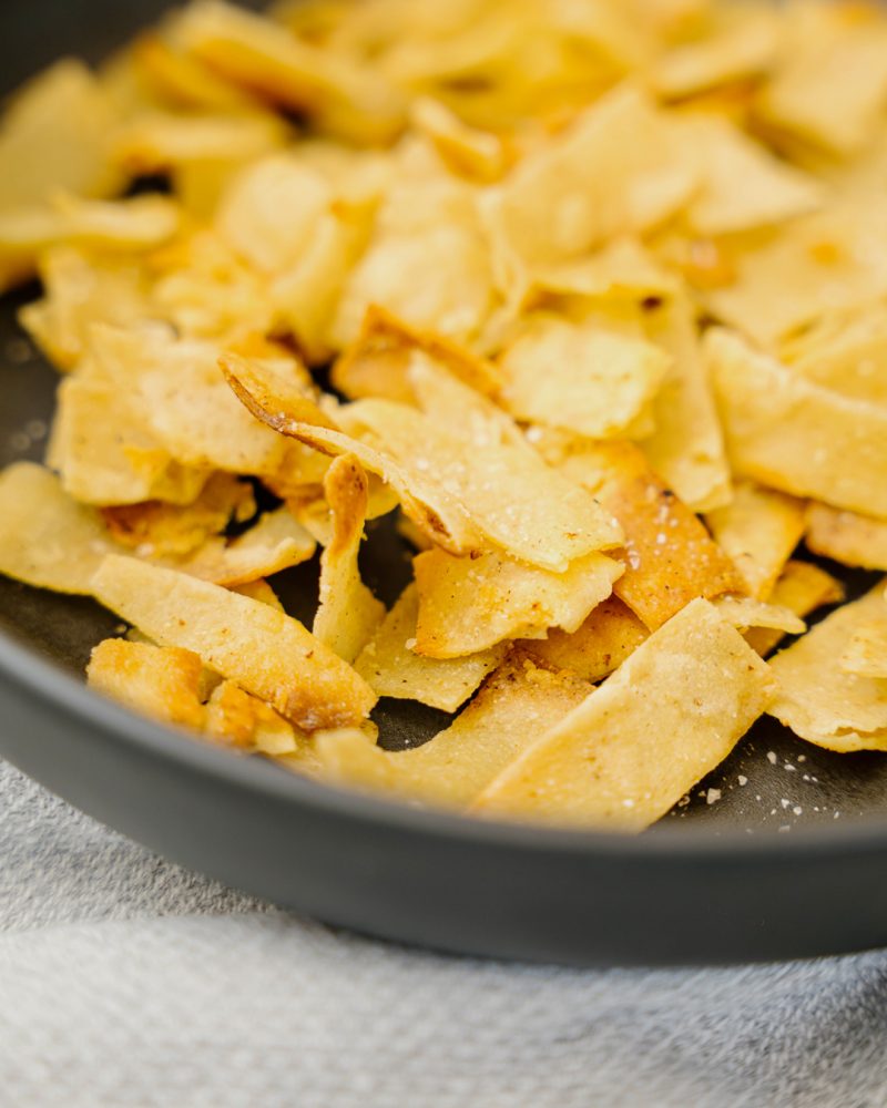 Crisp, toasted pieces of pita bread in a black skillet.