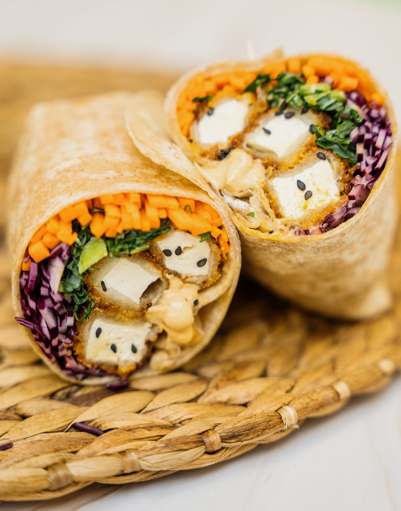 Wrap tofu croustillant avec laitue, carottes et oignon, servi avec tortillas Mejicano et graines de sésame.